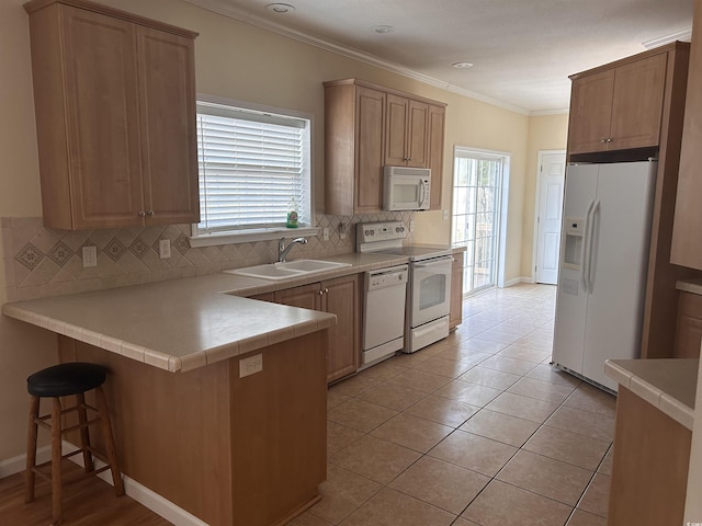 kitchen featuring a breakfast bar, tasteful backsplash, sink, crown molding, and white appliances