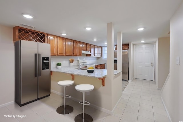 kitchen with stainless steel refrigerator, sink, stainless steel fridge, kitchen peninsula, and light stone countertops