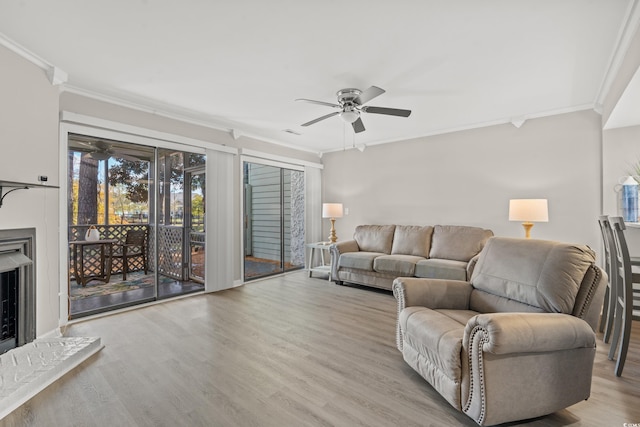 living room featuring ceiling fan, ornamental molding, and light hardwood / wood-style floors