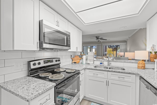 kitchen with sink, appliances with stainless steel finishes, white cabinetry, tasteful backsplash, and kitchen peninsula