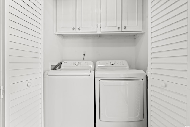 clothes washing area with cabinets and washer and dryer