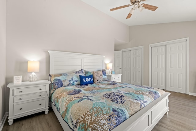 bedroom with lofted ceiling, multiple closets, light hardwood / wood-style flooring, and ceiling fan