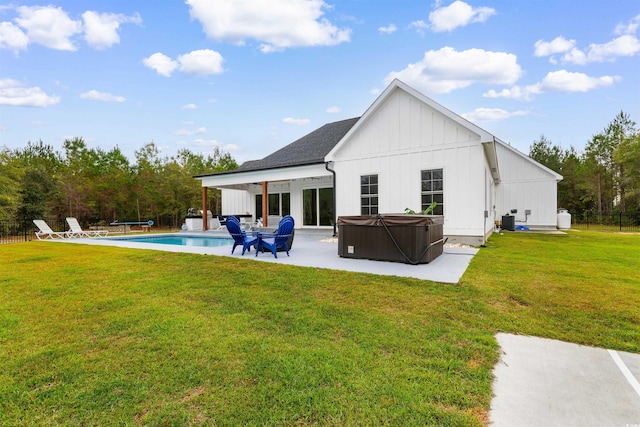 rear view of house featuring a lawn, a patio area, and a swimming pool with hot tub