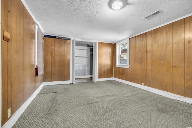 unfurnished bedroom featuring carpet flooring, a textured ceiling, and wooden walls