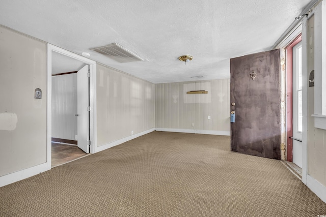 carpeted empty room featuring a textured ceiling and wooden walls