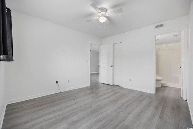 unfurnished bedroom featuring ceiling fan, light wood-type flooring, connected bathroom, and a closet