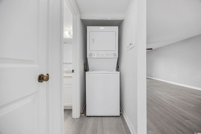 laundry room with stacked washer and dryer and light hardwood / wood-style floors