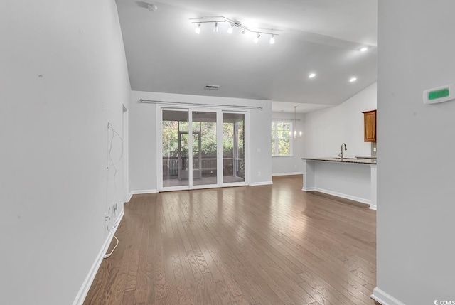 unfurnished living room featuring vaulted ceiling, sink, dark hardwood / wood-style floors, and an inviting chandelier