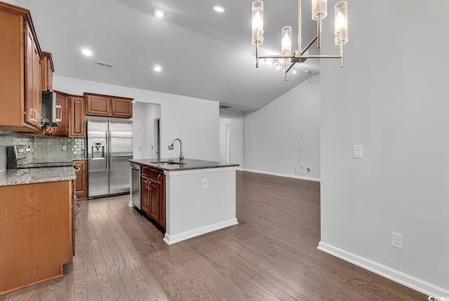 kitchen featuring sink, stainless steel appliances, decorative light fixtures, a kitchen island with sink, and hardwood / wood-style flooring