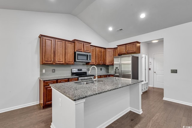 kitchen featuring appliances with stainless steel finishes, vaulted ceiling, a kitchen island with sink, sink, and dark hardwood / wood-style floors