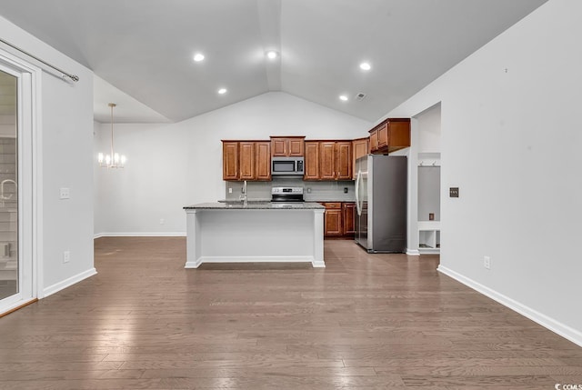 kitchen with lofted ceiling, dark wood-type flooring, an inviting chandelier, an island with sink, and appliances with stainless steel finishes