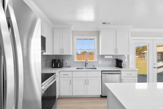 kitchen with stainless steel appliances, white cabinetry, and plenty of natural light