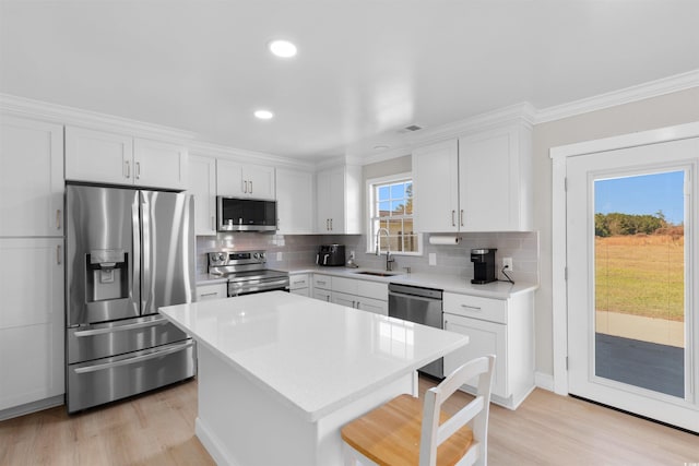 kitchen with white cabinets, a kitchen island, sink, and appliances with stainless steel finishes