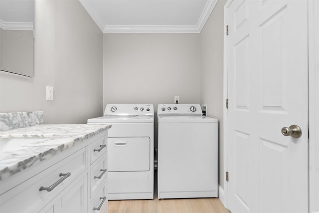 clothes washing area with washer and clothes dryer, light hardwood / wood-style floors, cabinets, and ornamental molding