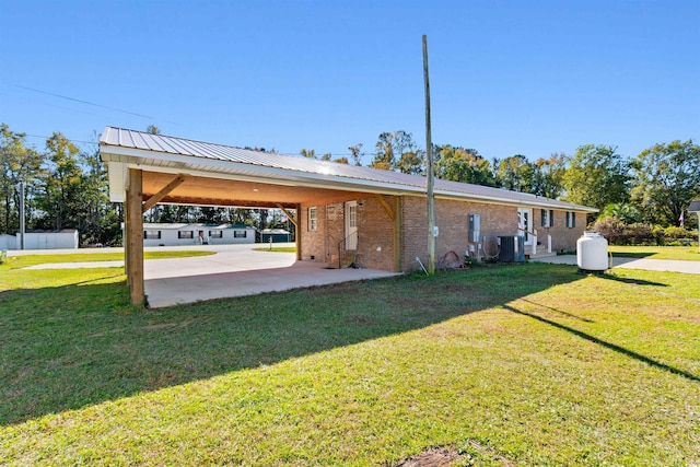 exterior space with a carport, a yard, and central AC