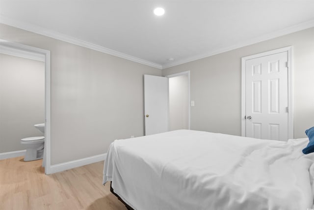 bedroom featuring light hardwood / wood-style flooring, ensuite bath, and crown molding