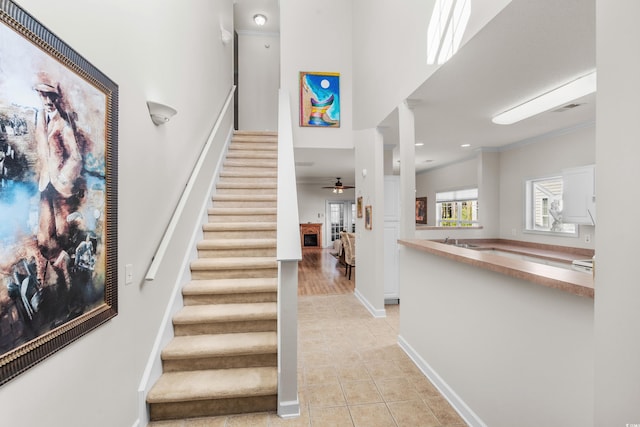 staircase featuring ceiling fan, hardwood / wood-style floors, and crown molding