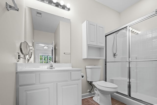 bathroom featuring tile patterned floors, vanity, toilet, and a shower with door