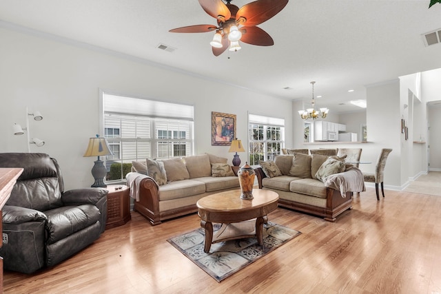 living room with ceiling fan with notable chandelier, light hardwood / wood-style flooring, and crown molding