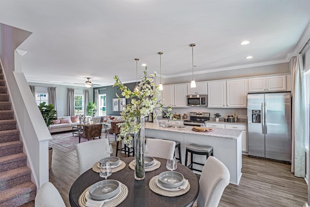 dining space with light hardwood / wood-style flooring, ornamental molding, and ceiling fan