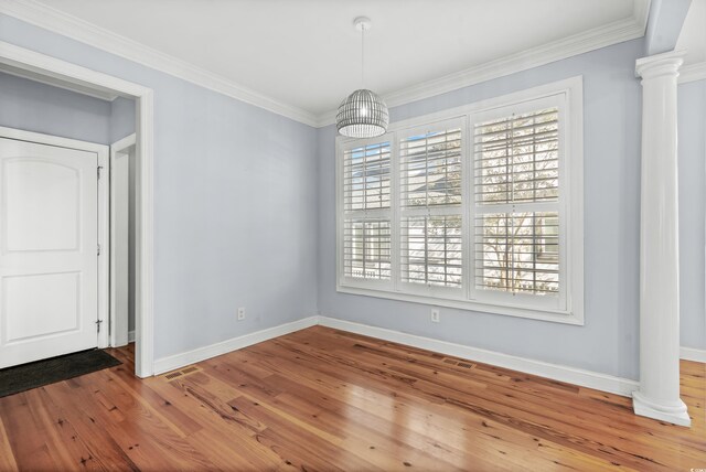 unfurnished dining area with wood-type flooring, ornate columns, and crown molding