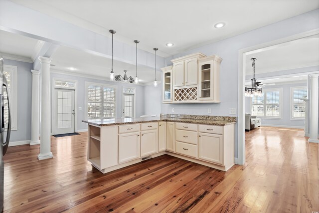 kitchen with ornate columns, hanging light fixtures, crown molding, hardwood / wood-style floors, and ceiling fan with notable chandelier