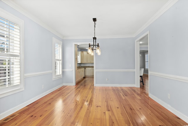 unfurnished dining area with light hardwood / wood-style floors, crown molding, and a wealth of natural light