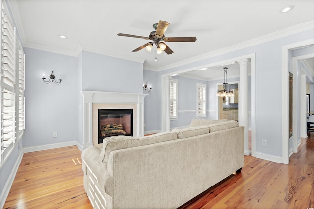 living room featuring ceiling fan with notable chandelier, light hardwood / wood-style floors, a healthy amount of sunlight, and crown molding