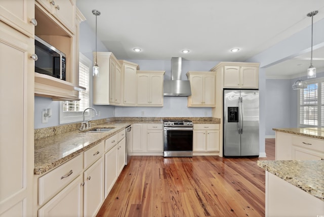 kitchen featuring sink, decorative light fixtures, wall chimney exhaust hood, appliances with stainless steel finishes, and plenty of natural light