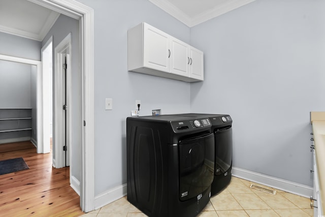 clothes washing area with washer and dryer, cabinets, crown molding, and light hardwood / wood-style flooring