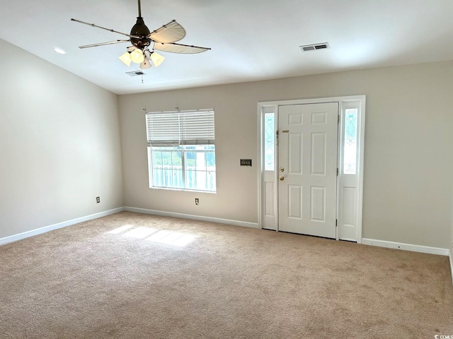 carpeted entryway with ceiling fan and plenty of natural light