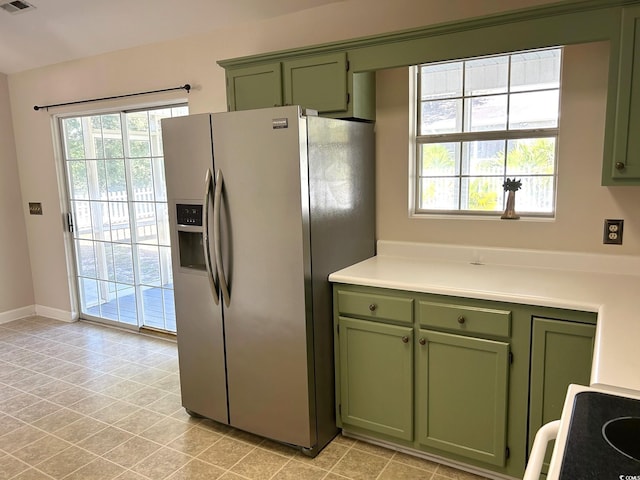 kitchen featuring stainless steel fridge with ice dispenser, stove, and green cabinetry