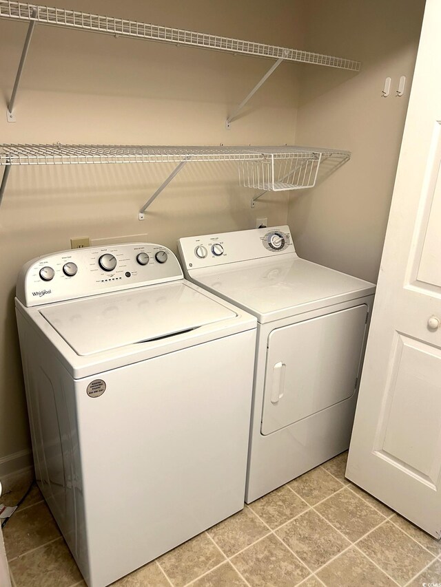 clothes washing area featuring light tile patterned floors and washer and clothes dryer