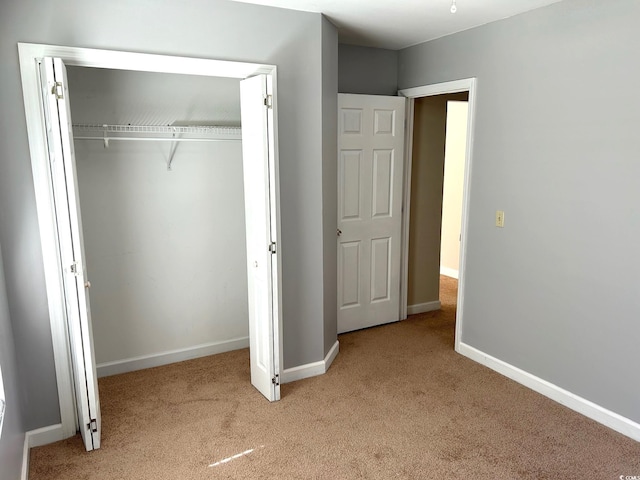 unfurnished bedroom featuring light colored carpet and a closet