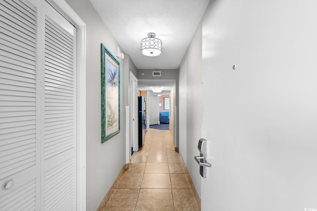 hall with light tile patterned floors and a textured ceiling