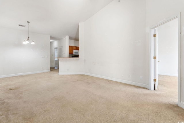 unfurnished living room with light colored carpet and an inviting chandelier