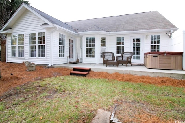 back of property with a lawn and a hot tub