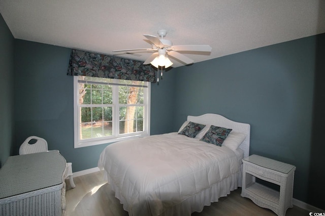 bedroom with a textured ceiling, hardwood / wood-style flooring, and ceiling fan