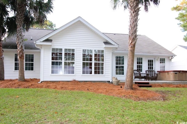 back of property with a yard, a hot tub, and a deck