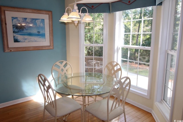 dining space with hardwood / wood-style floors and a notable chandelier