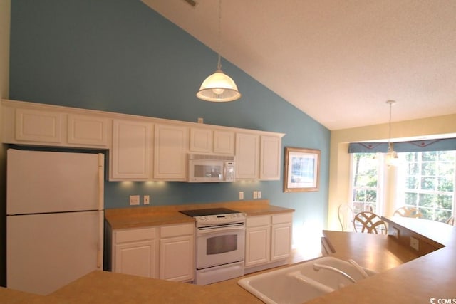 kitchen featuring white appliances, vaulted ceiling, sink, decorative light fixtures, and white cabinets