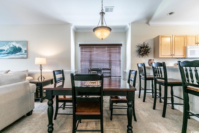 dining room featuring light colored carpet and ornamental molding