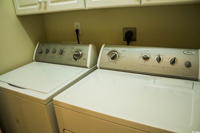 laundry room with separate washer and dryer and cabinets