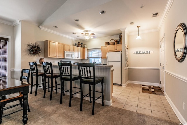 kitchen with decorative light fixtures, light brown cabinets, white appliances, and ornamental molding