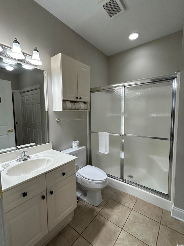 bathroom featuring toilet, vanity, tile patterned floors, and a shower with shower door