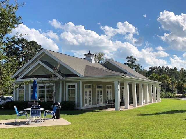 rear view of property featuring a lawn, french doors, and a patio