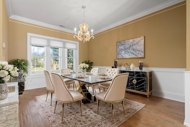 dining room with crown molding, a chandelier, and light wood-type flooring