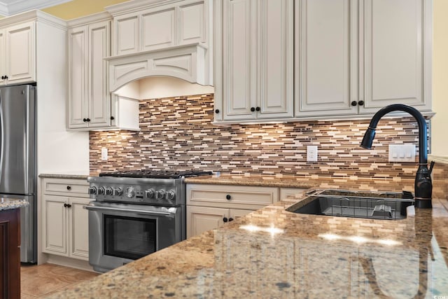 kitchen with light stone counters, appliances with stainless steel finishes, sink, and backsplash