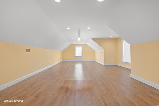 additional living space featuring vaulted ceiling and light hardwood / wood-style flooring