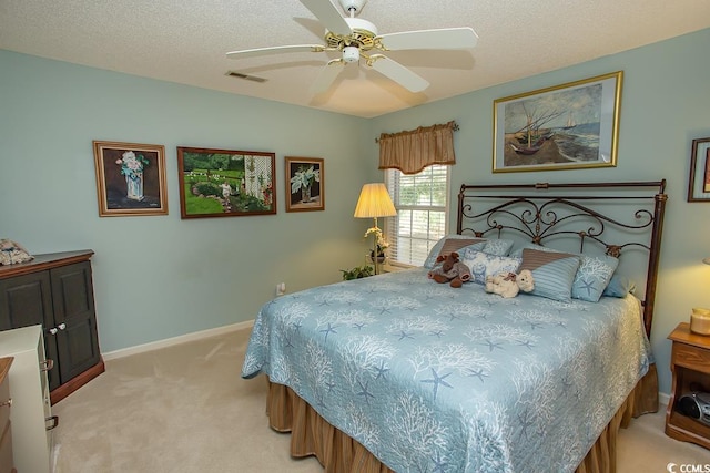 bedroom with ceiling fan, light carpet, and a textured ceiling